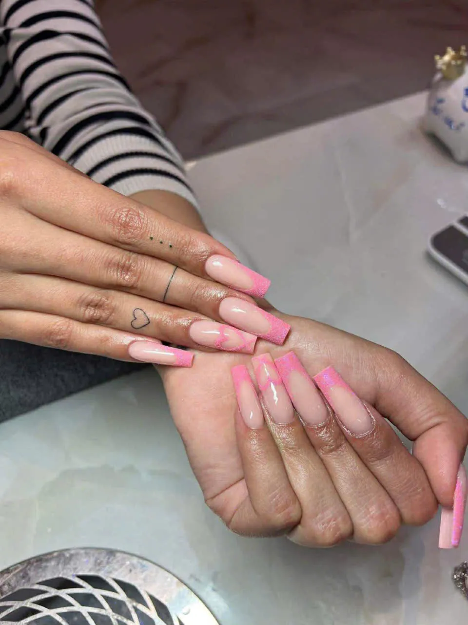 Long pink glitter French tip nails with heart accents