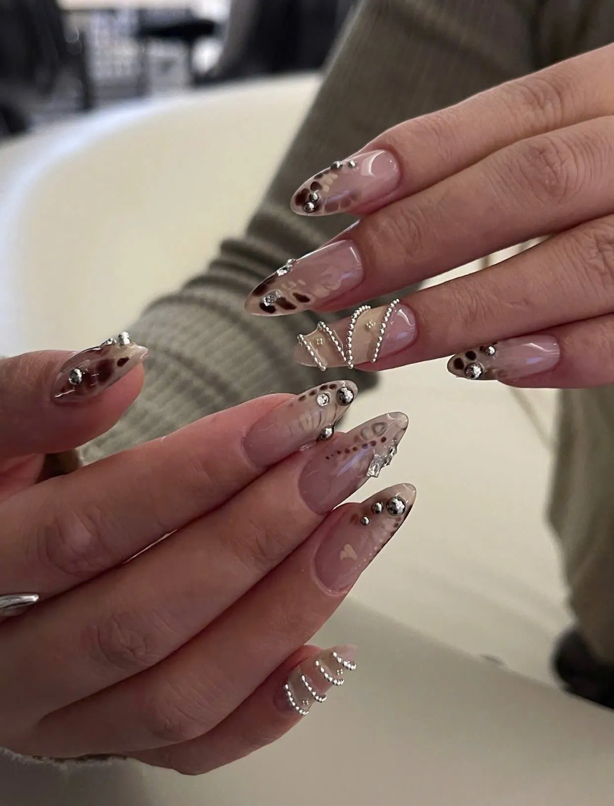 Nude almond nails with brown marble art, crystals and 3D butterfly
