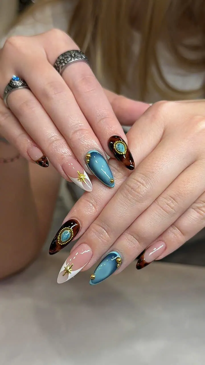 Almond nails with blue chrome, tortoise shell and gold cameo charms